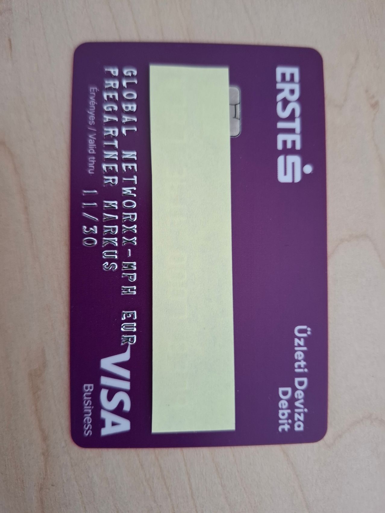 Eine lilafarbene Geschäfts-Debitkarte von Erste Bank mit Global Network. Die Karte trägt den Text VISA und das Datum 11/30 gültig bis. Die Karte liegt auf einer hölzernen Oberfläche.