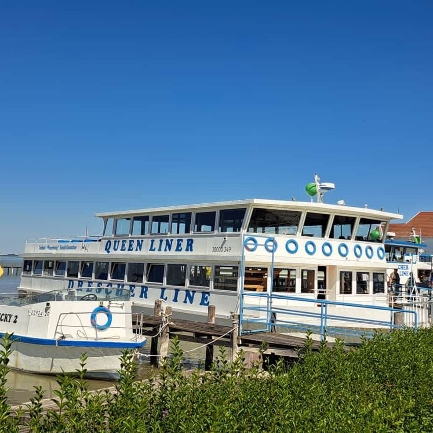 A large white ferry boat named Queen Liner is docked at a pier with a smaller boat, Ricky 2, nearby.