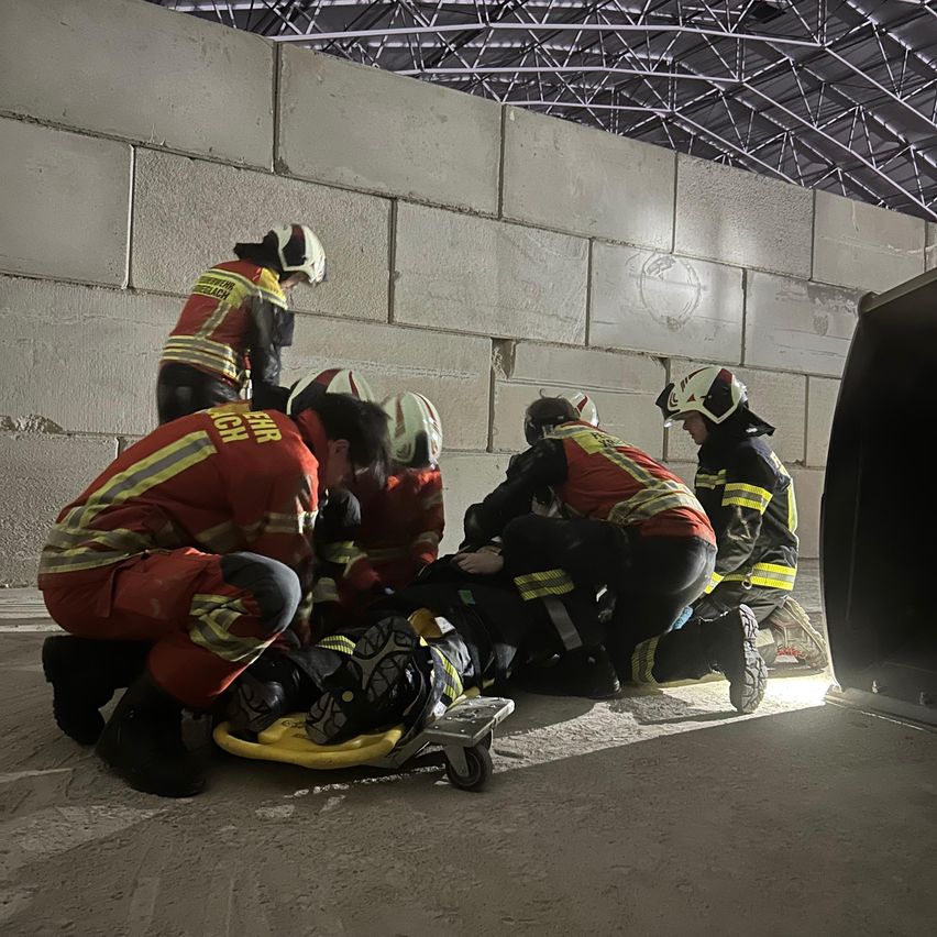 A group of firefighters are tending to an injured person on a stretcher inside a tunnel.