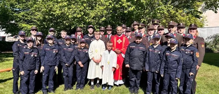 Eine Gruppe uniformierter Personen steht im Freien zusammen, einschließlich Kinder und Erwachsene, einige in Hüten und andere in religiöser Kleidung, posieren für ein Foto.
