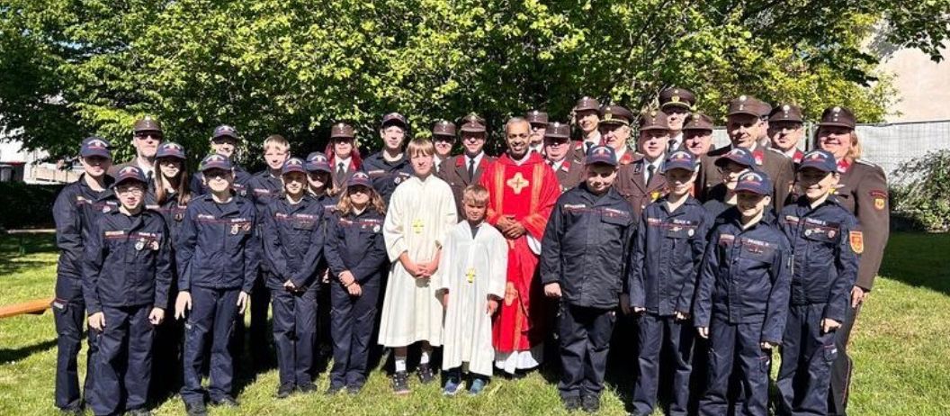 Eine Gruppe uniformierter Personen steht im Freien zusammen, einschließlich Kinder und Erwachsene, einige in Hüten und andere in religiöser Kleidung, posieren für ein Foto.