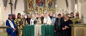 Eine Gruppe von Menschen versammelt sich in einer Kirche und steht vor einem Altar. Sie tragen Hüte und Gewänder. Der Altar ist mit Blumen, Kerzen und anderen Gegenständen geschmückt. Hinter ihnen befindet sich eine Wand mit einem Kruzifix und einer Statue. Das Bild hat einen Wasserzeichen mit dem Text 'STUFF'.