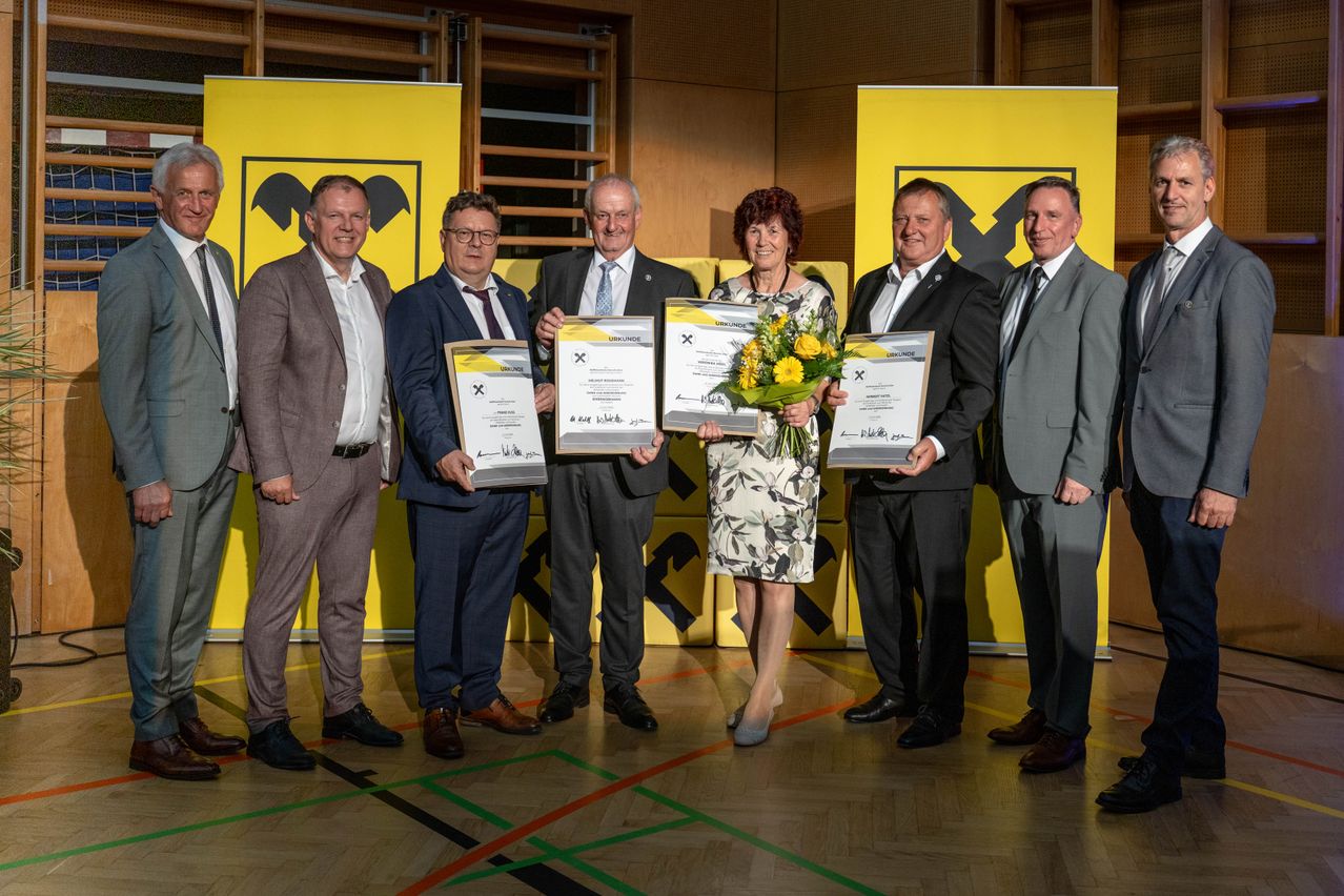 Five people are standing next to each other holding certificates and a bouquet of flowers in front of a yellow backdrop.