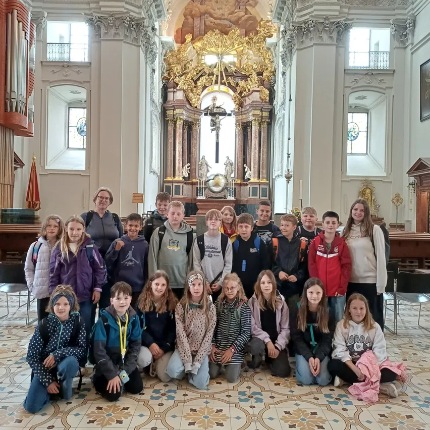 Eine Gruppe von Schülern und Lehrern posiert für ein Foto in einer Kirche mit aufwendiger Architektur.