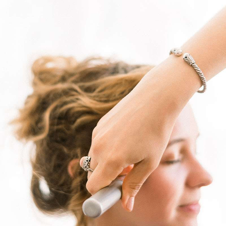 Eine Person lässt sich von einer anderen Person die Haare machen. Der Friseur hält einen Pinsel.