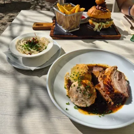 A table set with a plate of meat, vegetables, and a side of fries, along with a bowl of salad and a glass of wine.