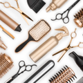 Eine Sammlung von goldenen und schwarzen Haarstyling-Werkzeugen auf weißem Hintergrund. Beinhaltet Bürsten, Scheren, Sprühflasche und Kämme.