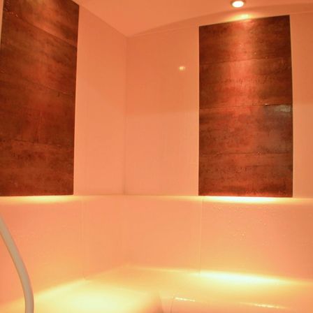Innenbereich eines Spas mit Kupferpaneelen an den Wänden und einer Badewanne mit Abfluss.