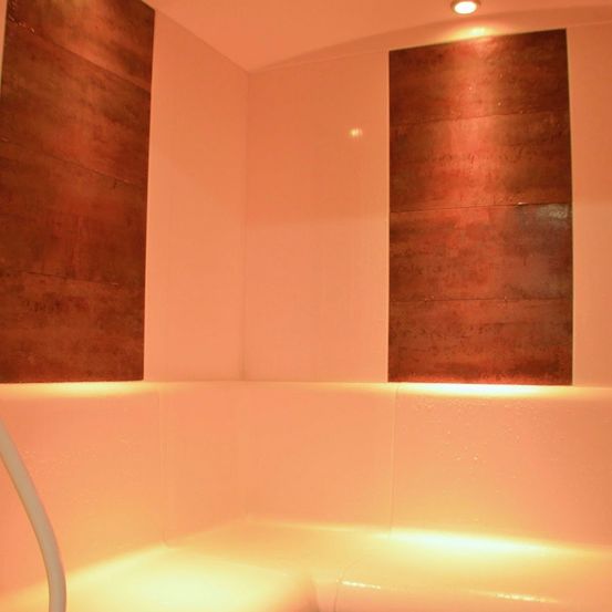 Innenbereich eines Spas mit Kupferpaneelen an den Wänden und einer Badewanne mit Abfluss.