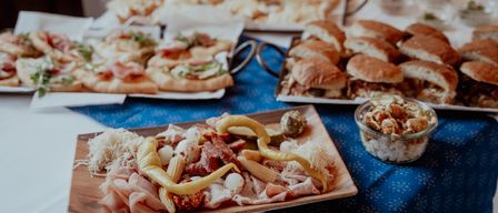 Ein Tisch mit verschiedenen Speisen, darunter Fleisch, Gemüse und Brot, für eine Mahlzeit oder Veranstaltung vorbereitet.