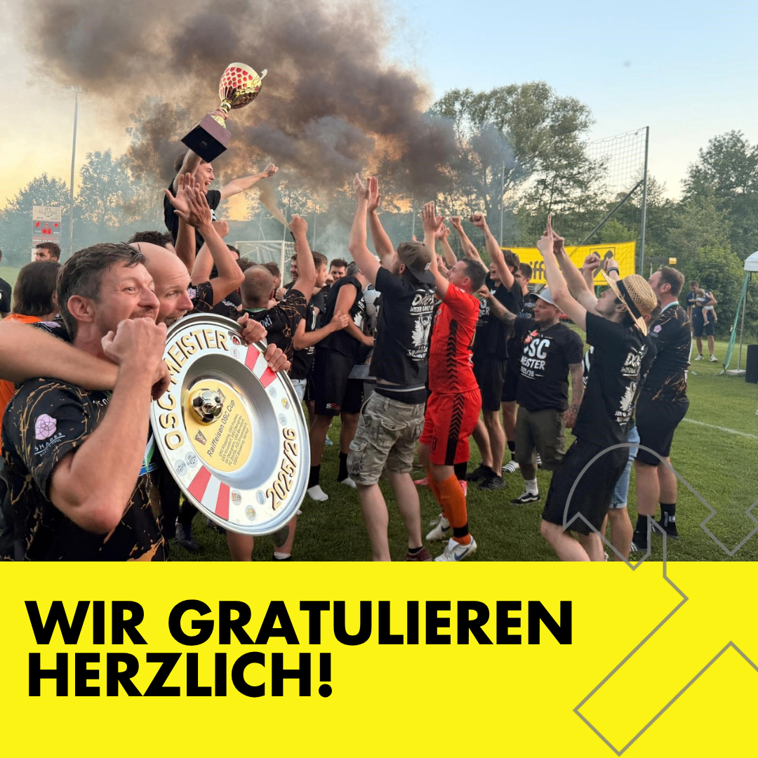 Eine Gruppe von Männern feiert einen Sieg mit Trophäen, einer hält einen Schild, auf einem Rasenfeld mit Rauch im Hintergrund.