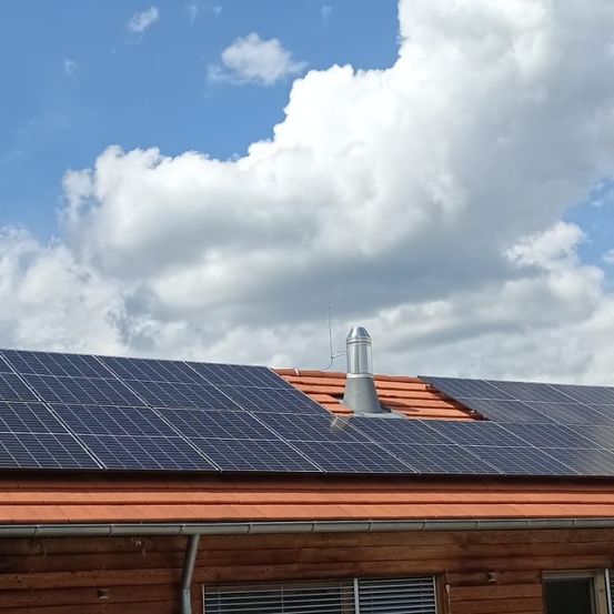 Ein Haus mit Solarmodulen auf dem Dach, unter einem bewölkten Himmel.