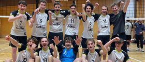 Eine Gruppe Volleyballspieler feiert gemeinsam auf einem Hallenplatz. Die Teammitglieder tragen weiße Trikots mit Nummern und einige tragen Brillen.