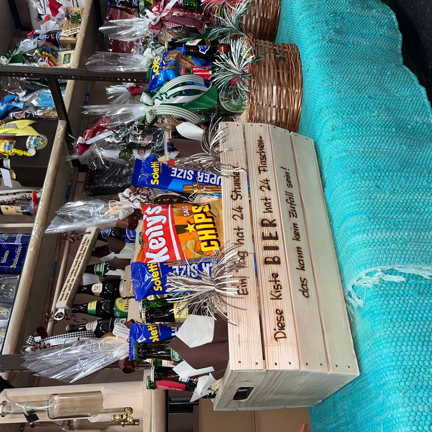Ein Holzkiste mit der Aufschrift 'Diese Kiste ist nicht 24'. Verschiedene Snacks und Getränke sind auf dem Regal über der Kiste platziert.