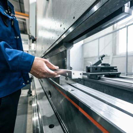 Bild enthält, Adult, Male, Man, Person, Building, Factory, Manufacturing, Workshop, Metalworking, Coat