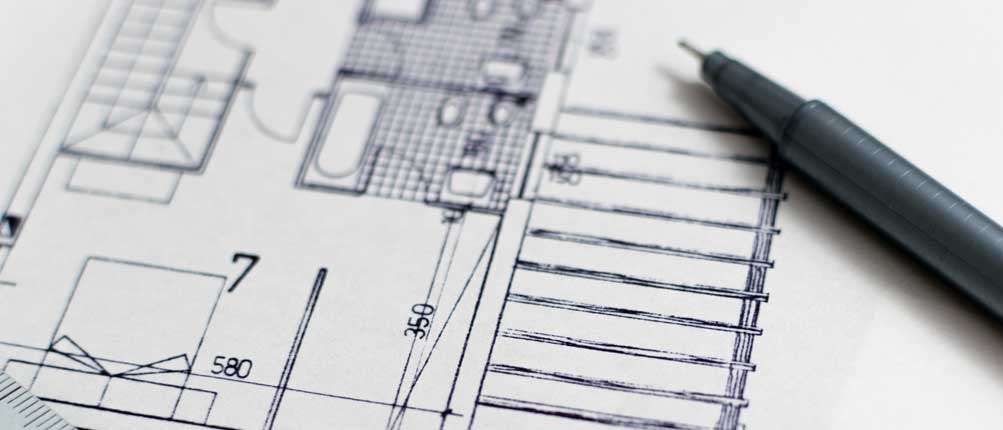 Bauplan eines Hauses mit einem Stift darauf. Es enthält eine Treppe, Abmessungen und Raumbezeichnungen.