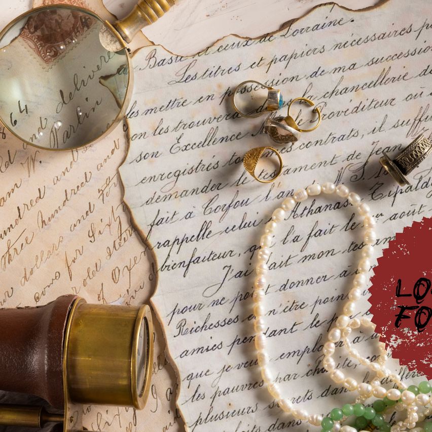 An antique magnifying glass, a brass telescope, and a pearl necklace are placed on an old, handwritten letter. The letter is partially torn and has French text. A few rings and a thimble are also on the letter.
