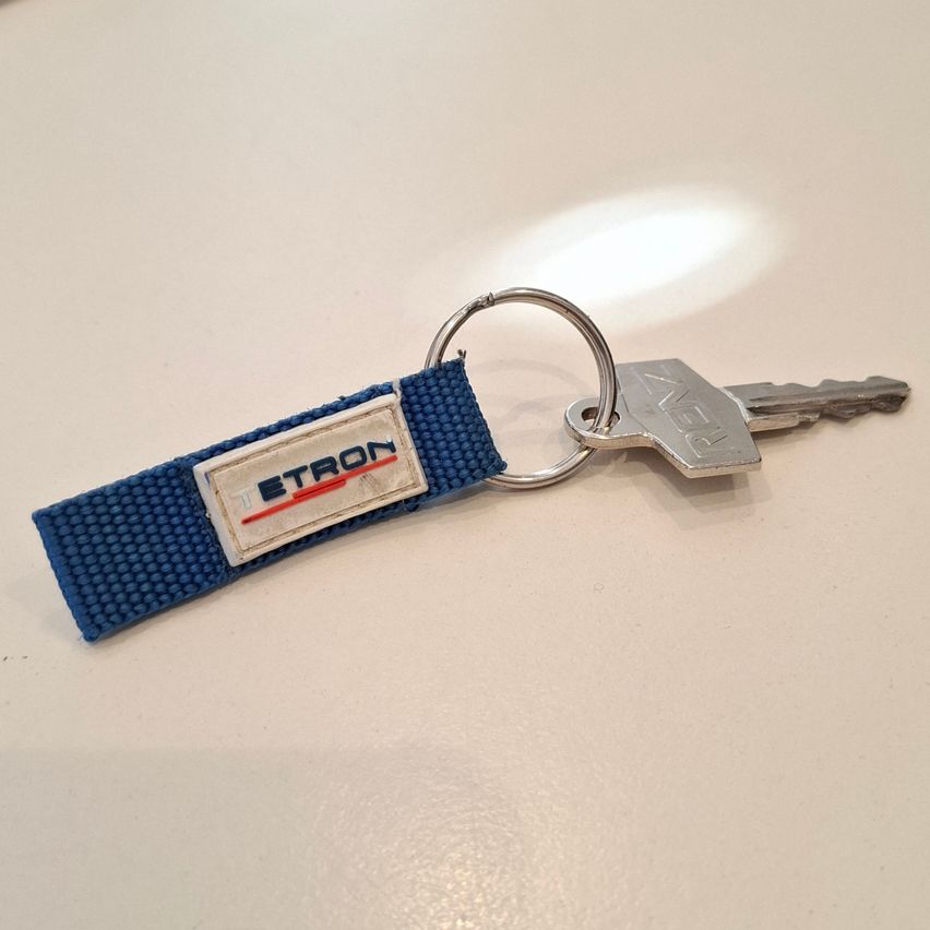 A blue keychain with a silver key attached, featuring the word 'Etron' in white and red on a white background.
