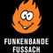 Eine Comic-Figur mit einem orangefarbenen, flammenartigen Körper, Augen und Mund, die auf einem schwarzen Hintergrund dargestellt wird. Der Text 'Funkenbande Fussach' steht in Weiß unter der Figur.