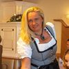 Eine blonde Kellnerin bedient einen Tisch mit zwei Frauen, während ein Mann zusieht. Das Restaurant hat ein traditionelles Interieur.