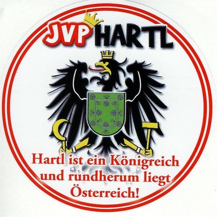 Das Bild zeigt das Logo von JVP Hartl, eine Monarchie mit einem schwarzen Adler, der einen Hammer und Sichel hält, einem roten Kreis und dem Text 'Hartl ist ein Königreich und ringsum liegt Österreich!'.