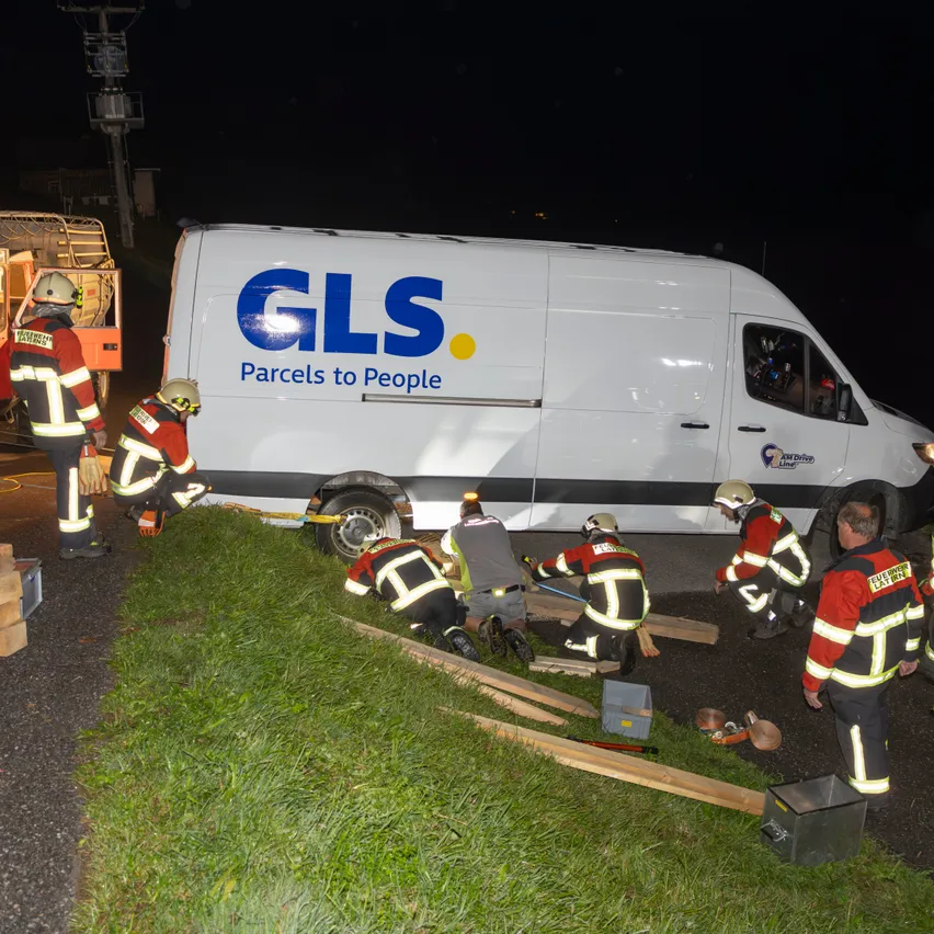 Feuerwehrleute arbeiten daran, einen feststeckenden GLS-Lieferwagen von einem Grashang zu entfernen, in der Nacht.