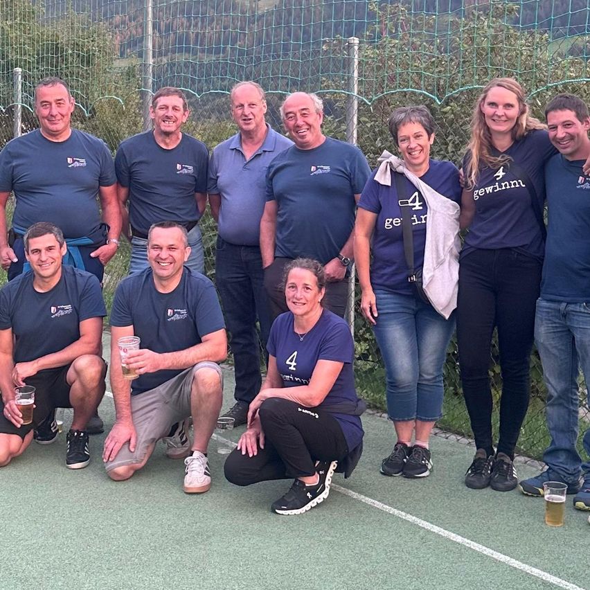 Eine Gruppe von Menschen posiert für ein Foto auf einem Tennisplatz.