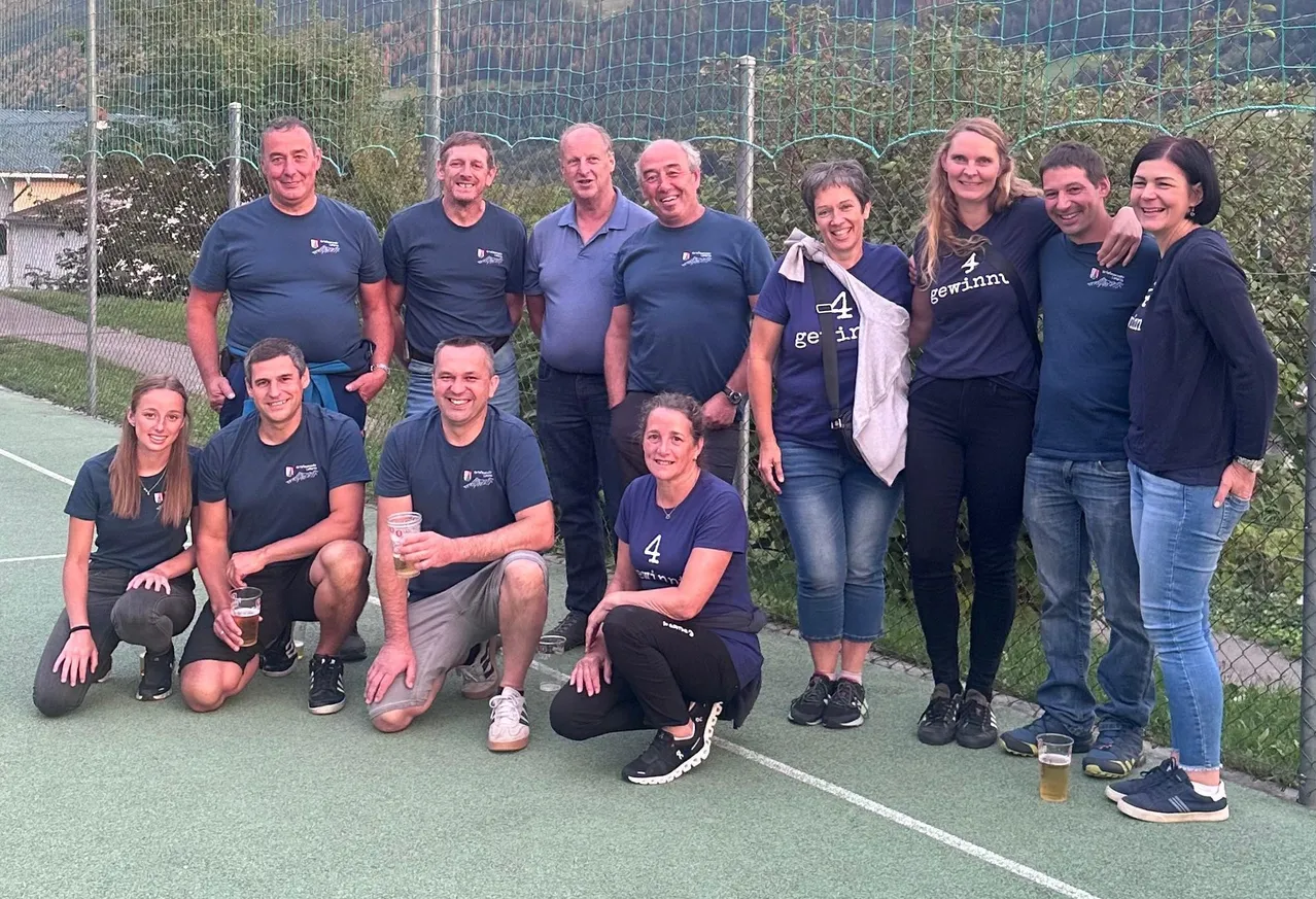 Eine Gruppe von Menschen posiert für ein Foto auf einem Tennisplatz.