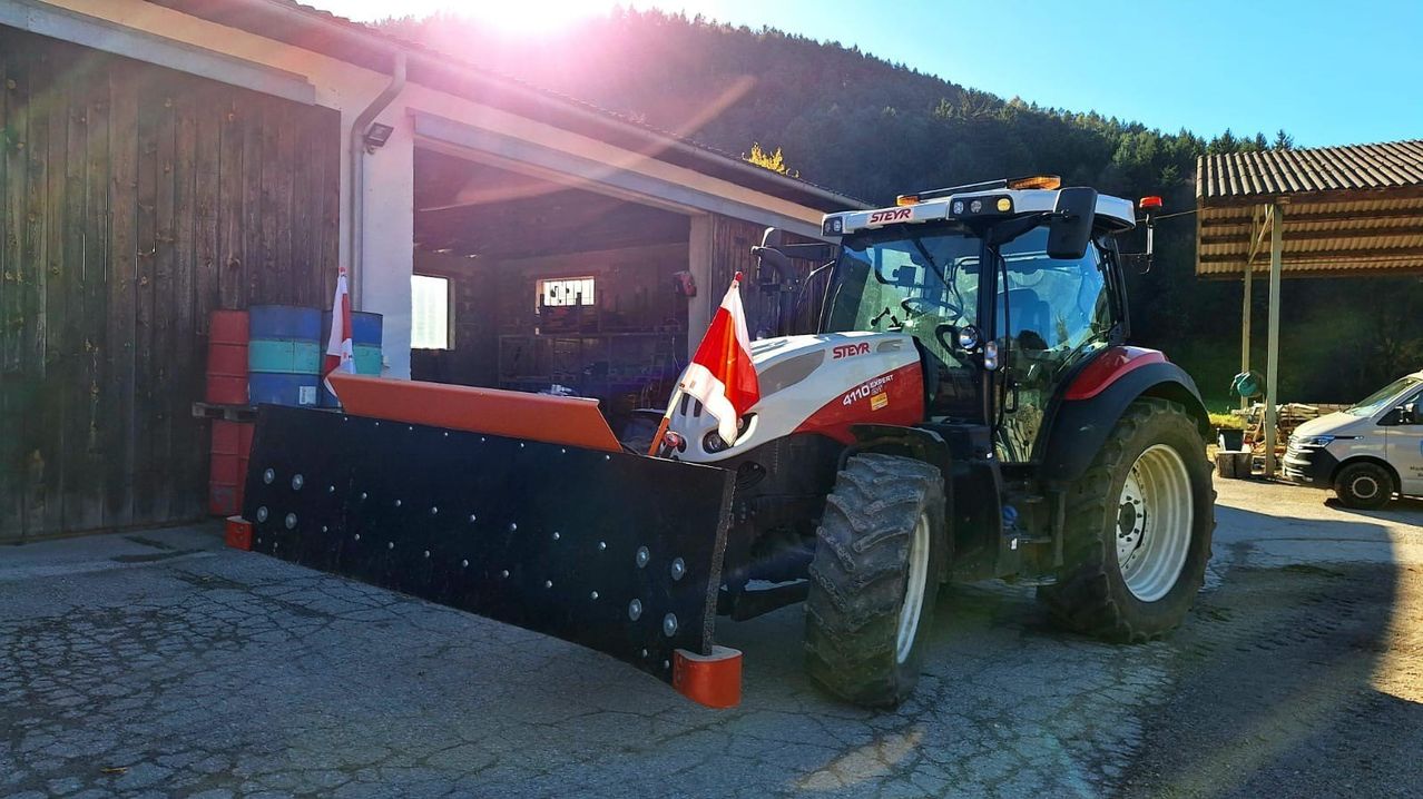 Ein Traktor mit einem Pflug steht in einer Garage mit einer Fahne an der Seite.