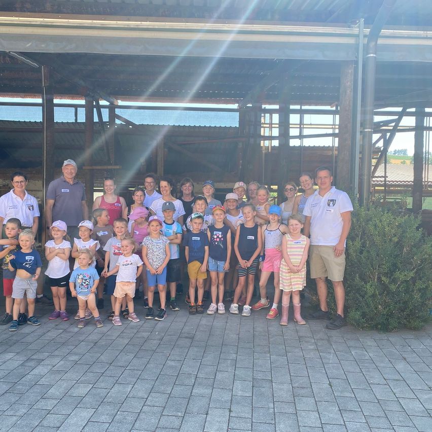 A group of children and adults pose for a photo in front of a building under construction.