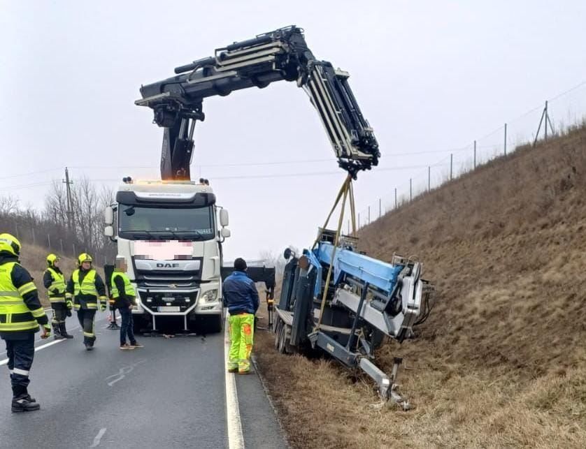 Ein Kran hebt einen beschädigten LKW von der Straßenseite. Mehrere Personen in Warnwesten stehen in der Nähe.