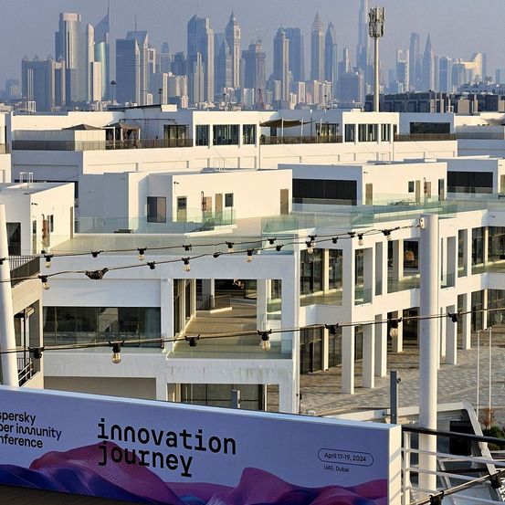 Eine moderne Stadtlandschaft mit zahlreichen weißen Gebäuden und Wolkenkratzern, eines davon mit einem Banner für 'Innovation Journey'. Die Stadt hat eine neblige Atmosphäre und viele Hochhäuser.