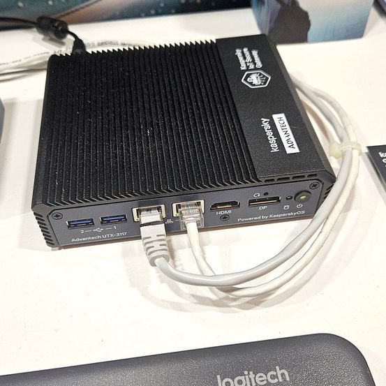 Ein schwarzes elektronisches Gerät mit mehreren Anschlüssen und angeschlossenen Kabeln, gekennzeichnet als Advantech UTx-3117, betrieben durch KasperskyOS.