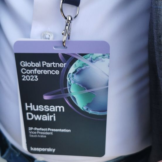 Eine Person trägt ein lila Lanyard mit dem Text 'Global Partner Conference 2023'. Es zeigt eine Erde und den Namen 'Hussam Dwair'. Er ist Vizepräsident aus Saudi-Arabien.