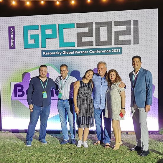 Fünf Personen, drei Männer und zwei Frauen, stehen zusammen vor einem großen Hintergrund für die Kaspersky Global Partner Conference 2021.