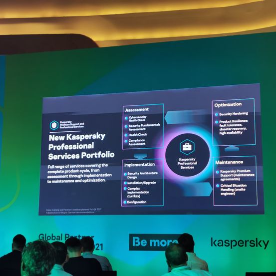 Ein Präsentationsbildschirm zeigt das neue Kaspersky Professional Services Portfolio. Es umfasst Bewertung, Implementierung und Wartung. Zu den wichtigsten Diensten gehören Cybersicherheits-Gesundheitschecks, Sicherheitsarchitekturdesign und Installation. Die Präsentation ist vor einem grünen Hintergrund.