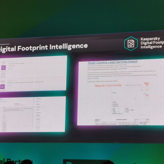 Ein Folienvortrag auf einem großen Bildschirm zeigt 'Digital Footprint Intelligence' und ein Textfeld über einen Datendiebstahl bei South Carolina Legal Services. Details zum Diebstahl sind im Textfeld angezeigt.