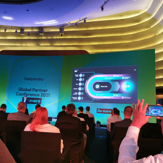 Publikum bei der Kaspersky Global Partner Conference 2021. Eine Person zeichnet die Präsentation auf einer großen Leinwand auf.