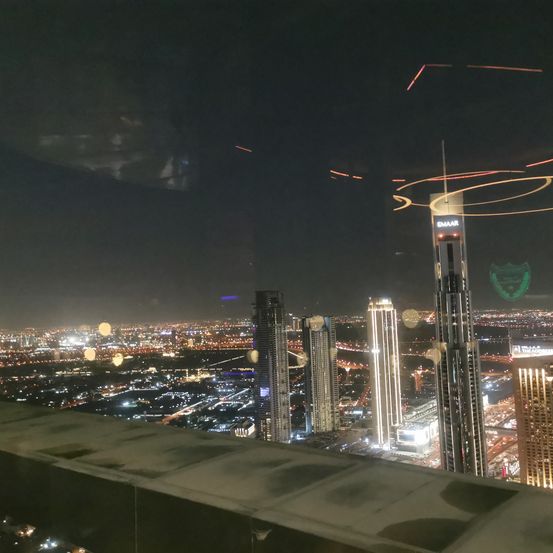 Ein Blick von einem Wolkenkratzer bei Nacht zeigt eine Skyline der Stadt mit vielen beleuchteten Hochhäusern.