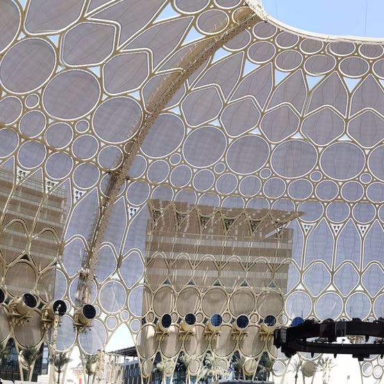 Eine große architektonische Struktur mit komplizierten geometrischen Mustern und goldenen Akzenten. Die Struktur besteht aus einer Reihe überlappender kreisförmiger Formen, die einen Baldachin-Effekt erzeugen.