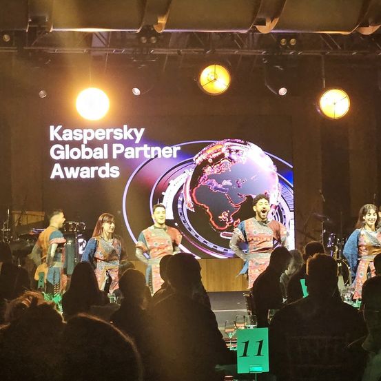 Eine Gruppe von Darstellern auf der Bühne bei den Kaspersky Global Partner Awards mit einem Weltkarten-Hintergrund und Publikum.