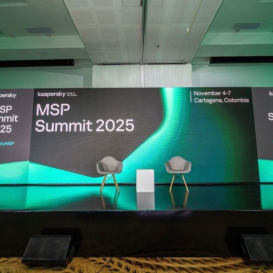 Bühnenaufbau für die MSP Summit 2025 Veranstaltung mit zwei leeren Stühlen, einem Hintergrund mit Kaspersky Branding und einem grünen und schwarzen Design. Die Bühne ist von grünem Licht beleuchtet.