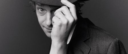 Ein Schwarz-Weiß-Foto zeigt einen Mann mit Hut, der sich mit einer Hand die Stirn hält. Er hat eine Tätowierung auf seinem linken Arm.