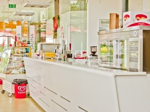 Ein Innenladen mit Theke, Mülleimer und Kühlschrank. Die Theke hat mehrere Gegenstände, einschließlich einer Kaffeemaschine.