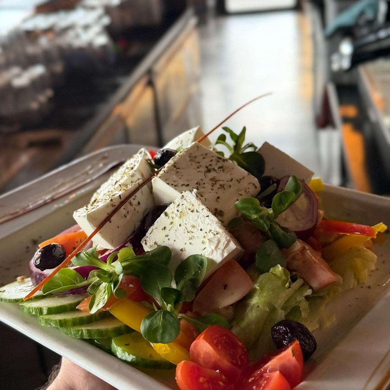 Ein Teller mit griechischem Salat mit Feta-Käse, Tomaten, Gurken, Oliven und verschiedenen Gemüsesorten.