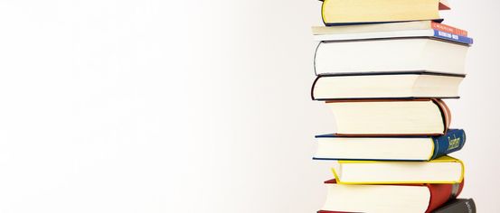 Ein vertikaler Stapel von Büchern mit farbenfrohen Buchrücken vor weißem Hintergrund.