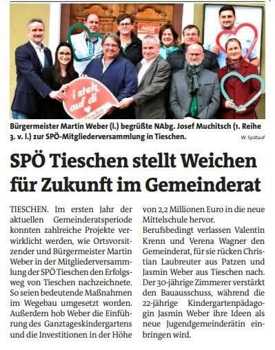 Eine Gruppe von Personen, darunter Beamte und Gemeindemitglieder, versammelt sich, hält ein Schild hoch und posiert für ein Foto. Das Schild lautet 'i stelh auf di.' Der Kontext scheint sich auf Gemeindeveranstaltungen oder lokale Regierungsaktivitäten zu beziehen.