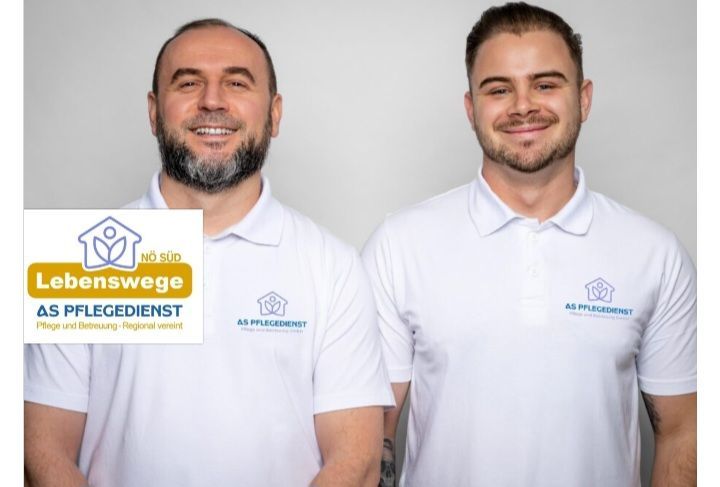 Zwei Männer in weißen Poloshirts mit Logos darauf lächeln für die Kamera. Der Mann auf der linken Seite hat ein Logo auf seinem linken Arm.