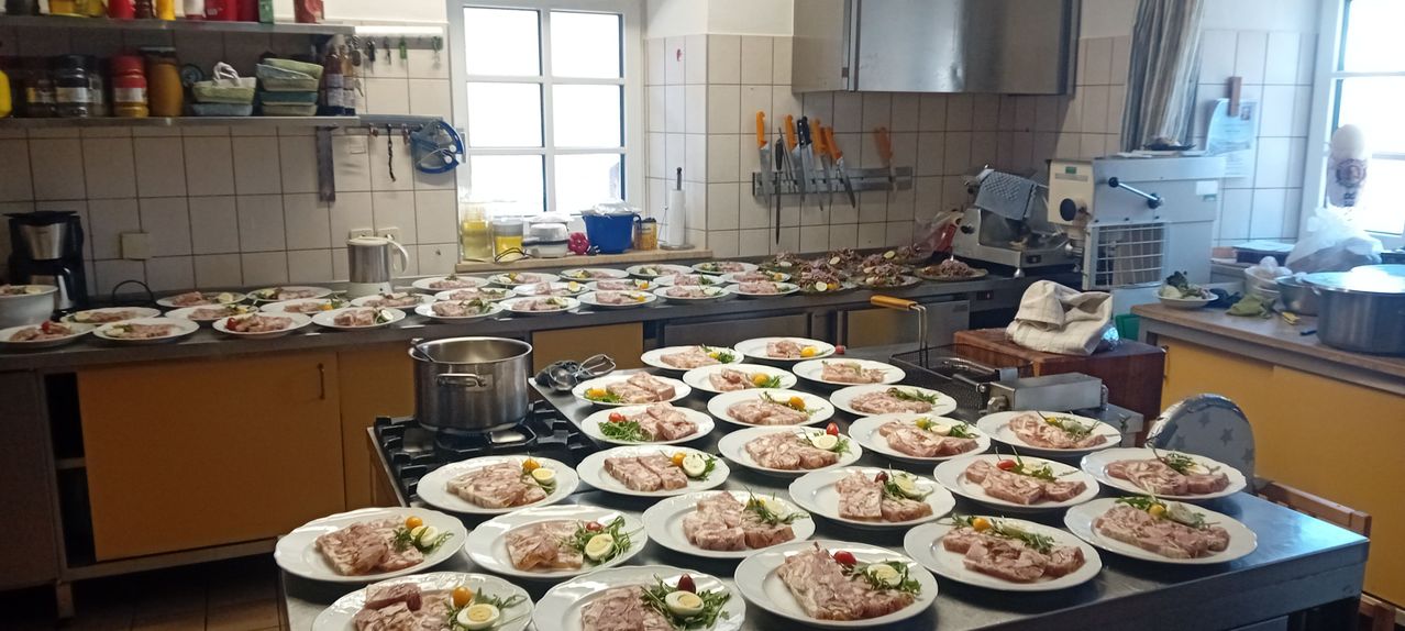 Eine Küche mit vielen Tellern mit Essen auf einem Tresen, einem Fenster dahinter und verschiedenen Küchenutensilien herum.