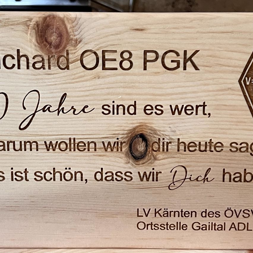 Eine Holzplakette zeigt 'Richard OE8 PGK'. Darunter steht in deutscher Sprache '50 Jahre sind es wert, wir wollten dir heute sagen, es ist schön, dass wir dich haben. LV Kärnten des ÖVSS Ortsstelle Gailtal ADL'.